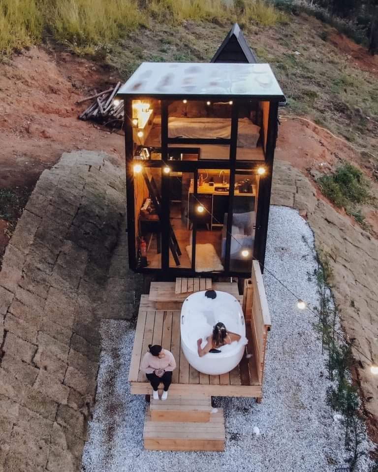 The meme features a serene, rustic cottagecore setting, with a small, cozy cabin nestled in a lush forest. The image depicts a woman relaxing in a hot tub, surrounded by nature, with a subtle caption that reads "when...