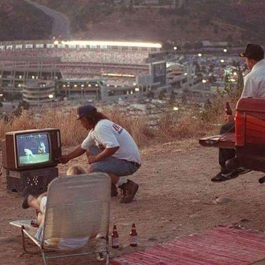 This meme is a still image from a 1990s TV show or movie, likely "Twin Peaks" or "The X-Files", where a character is sitting on a couch, looking at a TV that's showing a different character's face on the screen. The c...