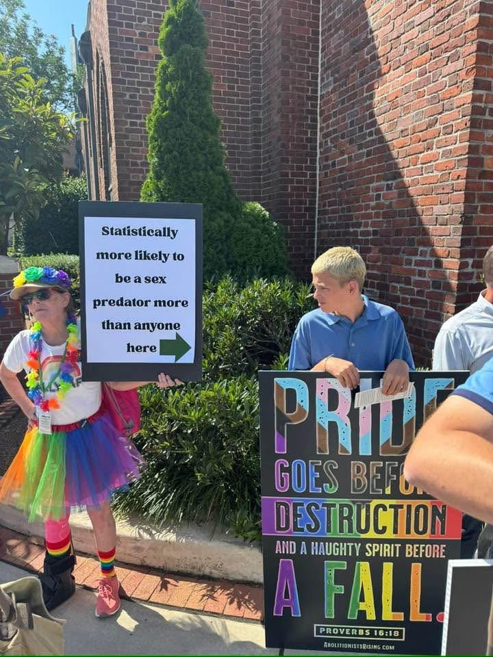 Okay, let's break down this image with the requested analytical lenses. It's a complex scene that invites multiple interpretations. **1. Visual Description** The photograph depicts two primary subjects against a backd...