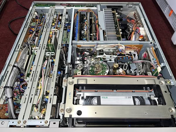 Okay, here's an analysis of the image of the opened video tape machine (VTR) broken down into the requested theoretical sections. It's important to note that applying complex theoretical frameworks to a single image i...