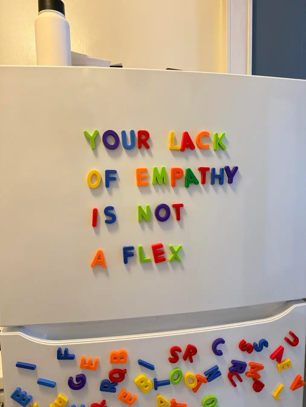 Okay, let's break down this image with the requested theoretical frameworks. ## Visual Description The image shows a white refrigerator door covered with magnetic letters. The letters are arranged to spell out the phr...