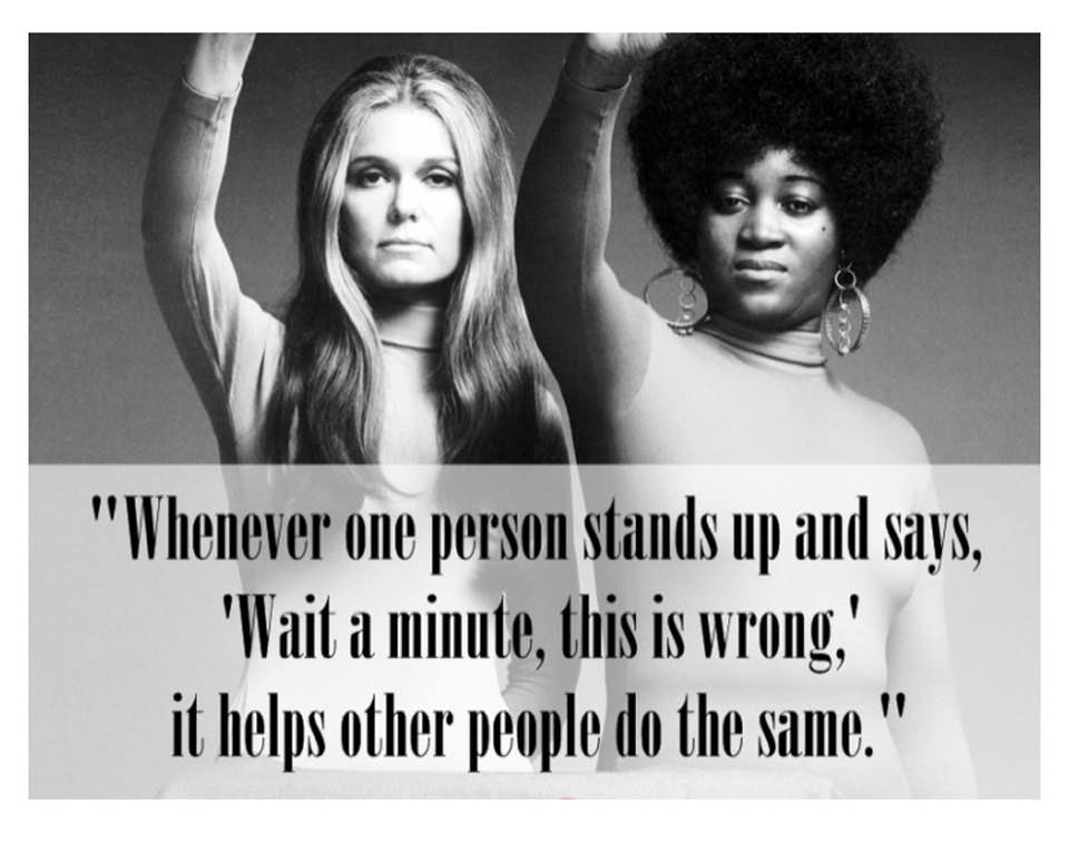 Okay, let's break down this image and its accompanying quote through the lenses you've requested. **Visual Description** The image is a black and white photograph featuring two women in close proximity, each raising a...