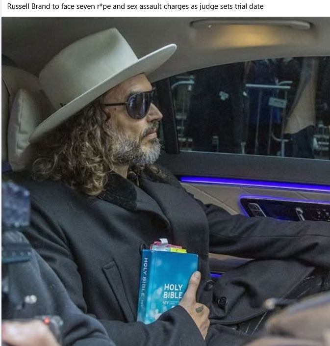 The image shows Russell Brand in a courtroom holding a book titled *The Mysteries of Christianity*, which features the words "Holy Bible" and "Mystery." To the reactionaries who create this meme, it is hilariously iro...