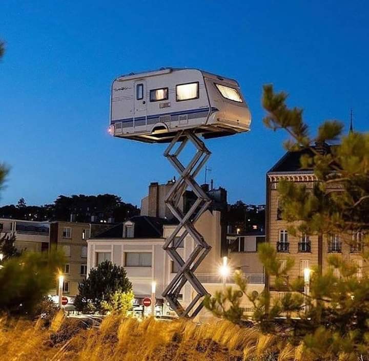 Okay, let's break down this image through the lenses you've requested. It’s a fascinating and layered visual, opening up several avenues for analysis. ## Visual Description The image depicts a white caravan (or camper...