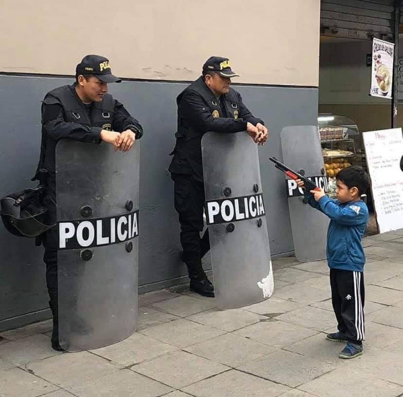 Okay, let's break down this image through several analytical lenses, focusing on the sections that are most relevant. **1. Visual Description** The photograph depicts two Peruvian police officers positioned behind lar...