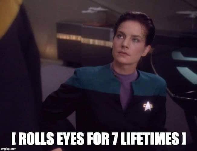 Okay, let's break down this image through the lenses you've provided. **Visual Description** The image is a screen capture from *Star Trek: Voyager* featuring Kate Mulgrew as Captain Kathryn Janeway. She is looking up...