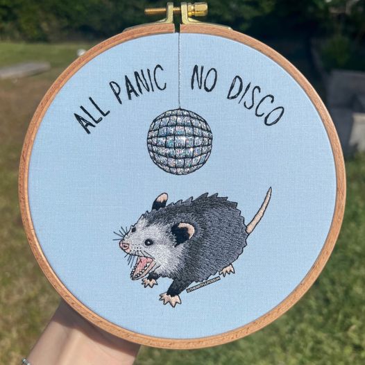 Okay, let's break down this embroidered hoop art through the requested lenses. **Visual Description** The image depicts a circular piece of hand embroidery, framed within a wooden embroidery hoop. The fabric is light...