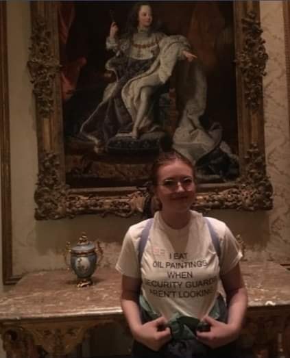 Okay, let's break down this image using the requested theoretical frameworks. **Visual Description** The image depicts a young person, likely female, sitting on the floor in front of a large, ornately framed Baroque o...