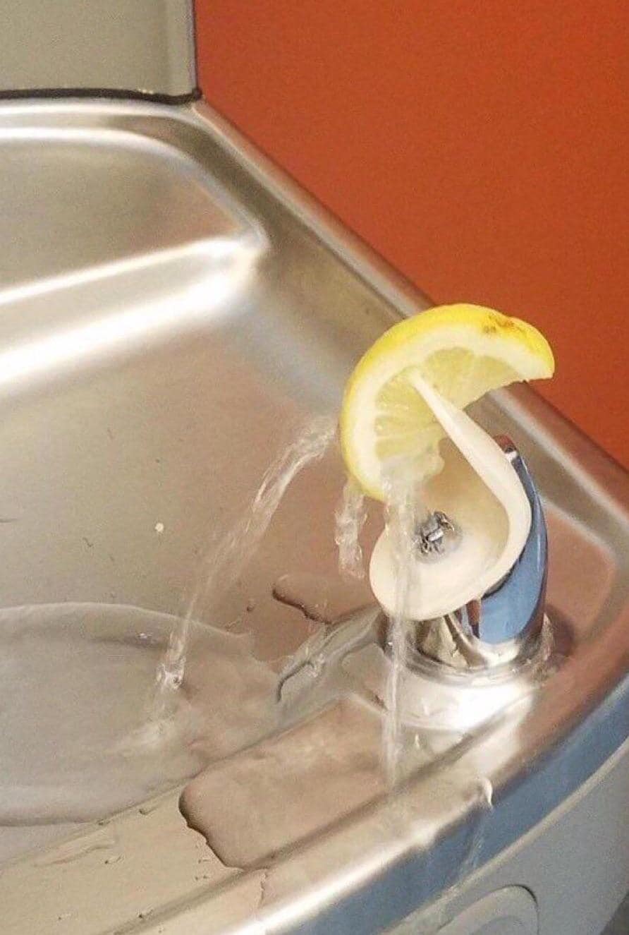 Okay, let's break down this image through the requested theoretical lenses. **Visual Description** The photograph depicts a close-up view of a stainless steel sink and faucet. Water is flowing from the faucet, and a h...
