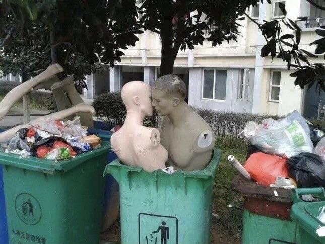 Okay, let's analyze the image you provided through the requested theoretical lenses. **Visual Description** The image depicts two life-sized mannequin heads seemingly kissing, positioned inside and on top of overflowi...