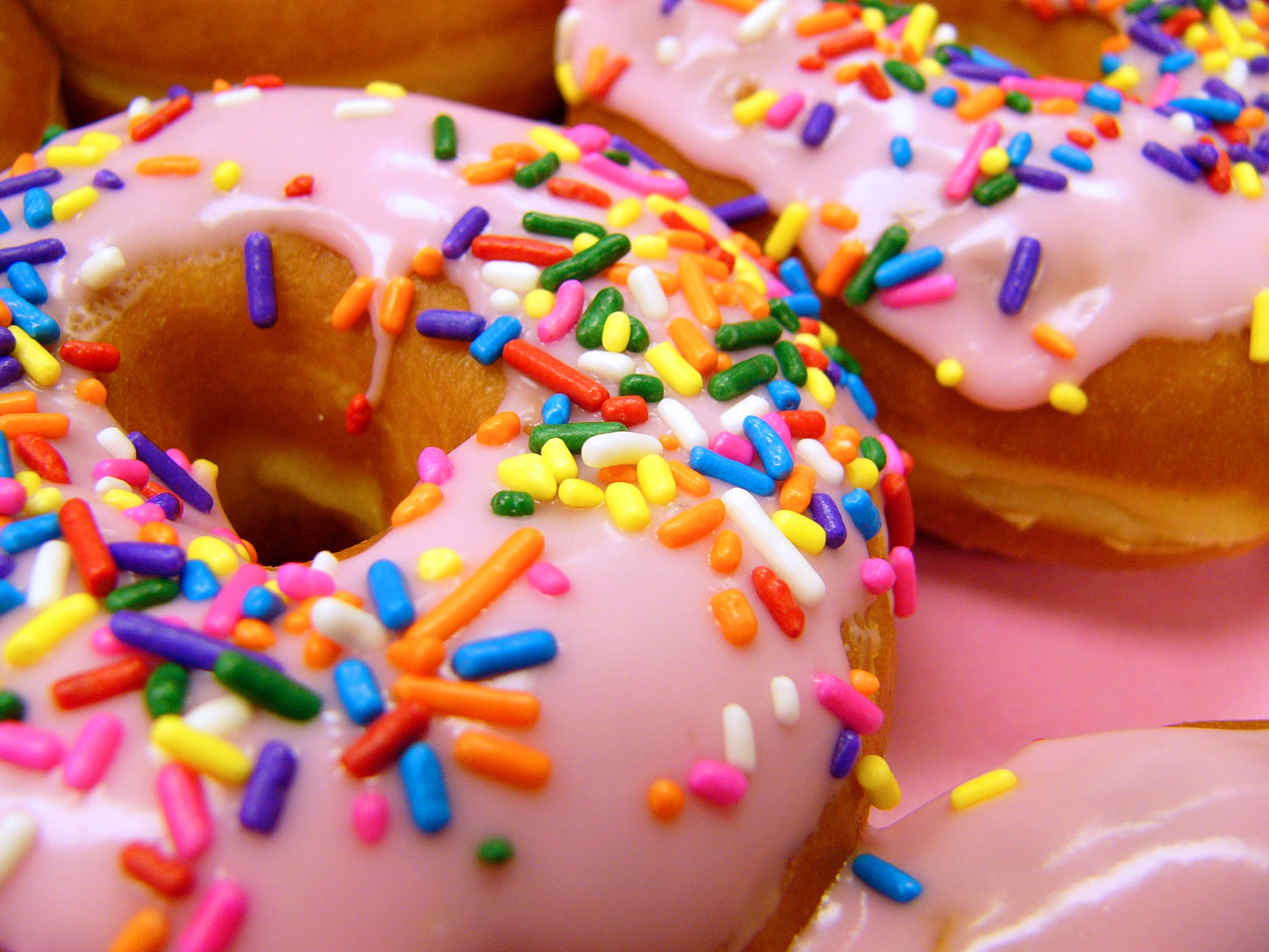 Okay, here's an analysis of the image of pink-frosted, sprinkle-covered donuts, broken down into the sections you requested, focusing where applicable. I'll indicate when a section doesn't *strongly* apply. ## Visual...