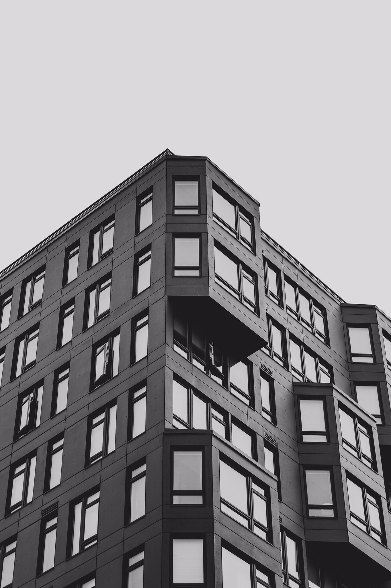 Okay, let's analyze the image of the building using the requested theoretical frameworks. **Visual Description** The image presents a low-angle, monochrome shot of a modern architectural structure. The building is cha...