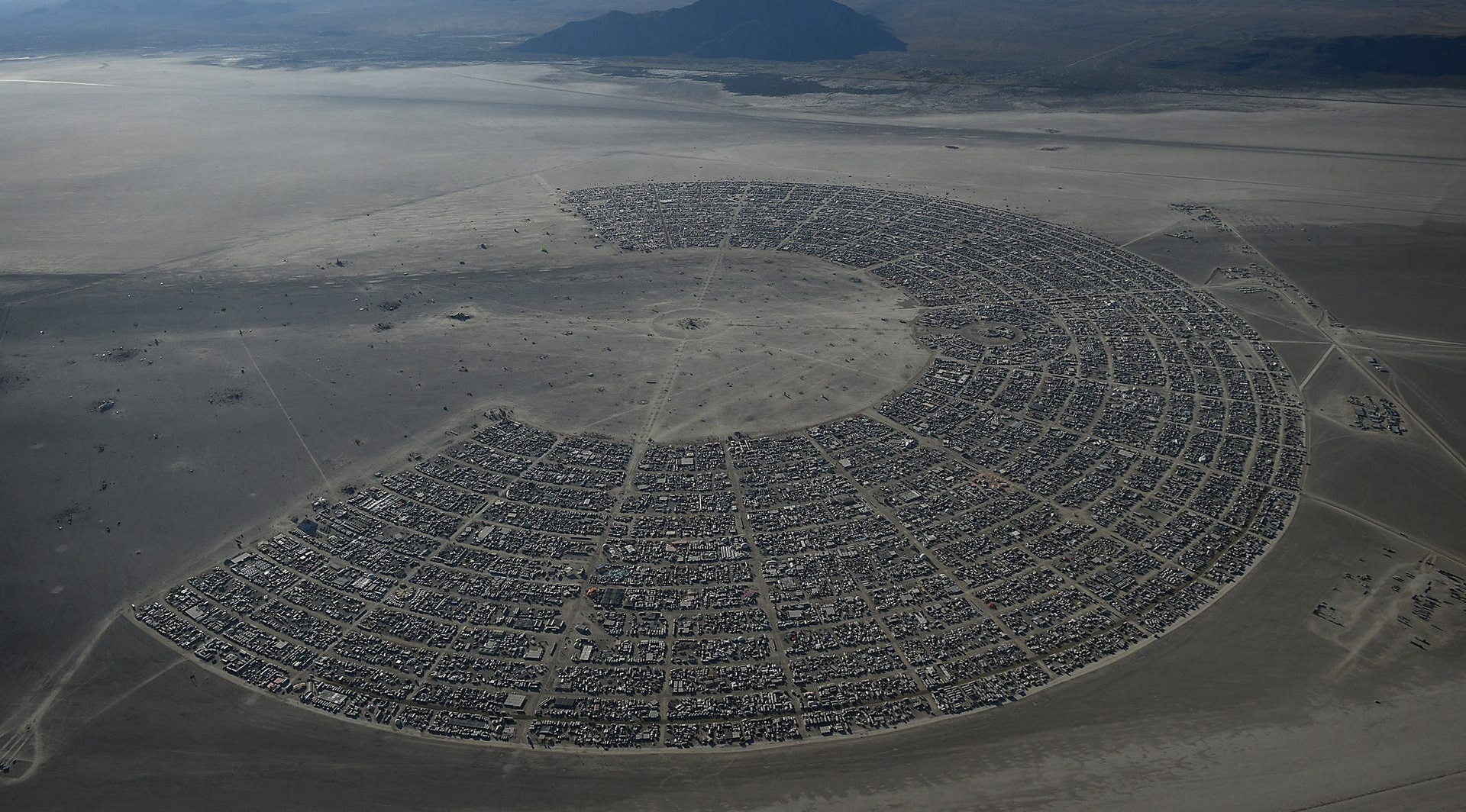 Okay, let's analyze the image of the Black Rock City, a temporary city constructed for the Burning Man festival, through the lenses you’ve requested. Keep in mind that applying these theories is interpretive, and mult...