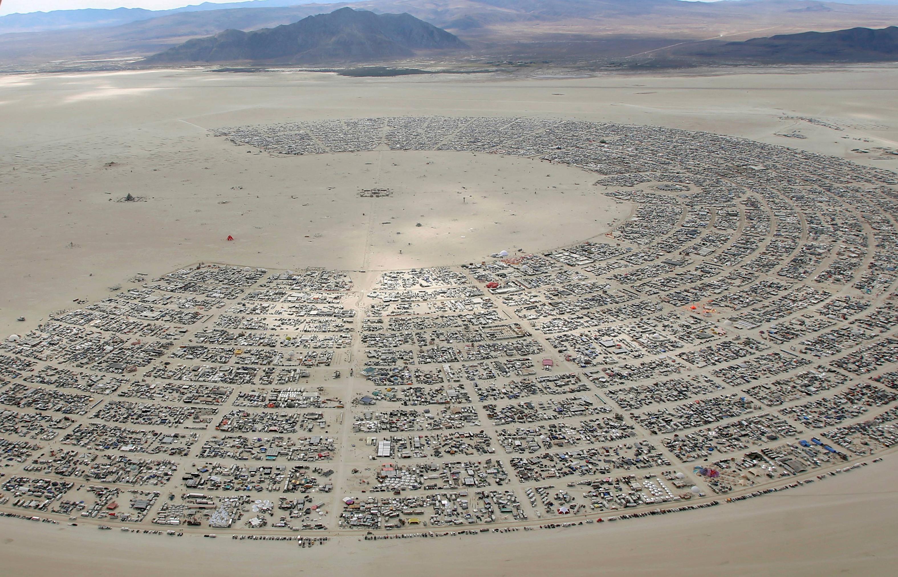 Okay, let's break down the image of Black Rock City (Burning Man) through several theoretical lenses. It's a rich image with plenty to unpack. **Visual Description** The image is an aerial view of a massive, temporary...