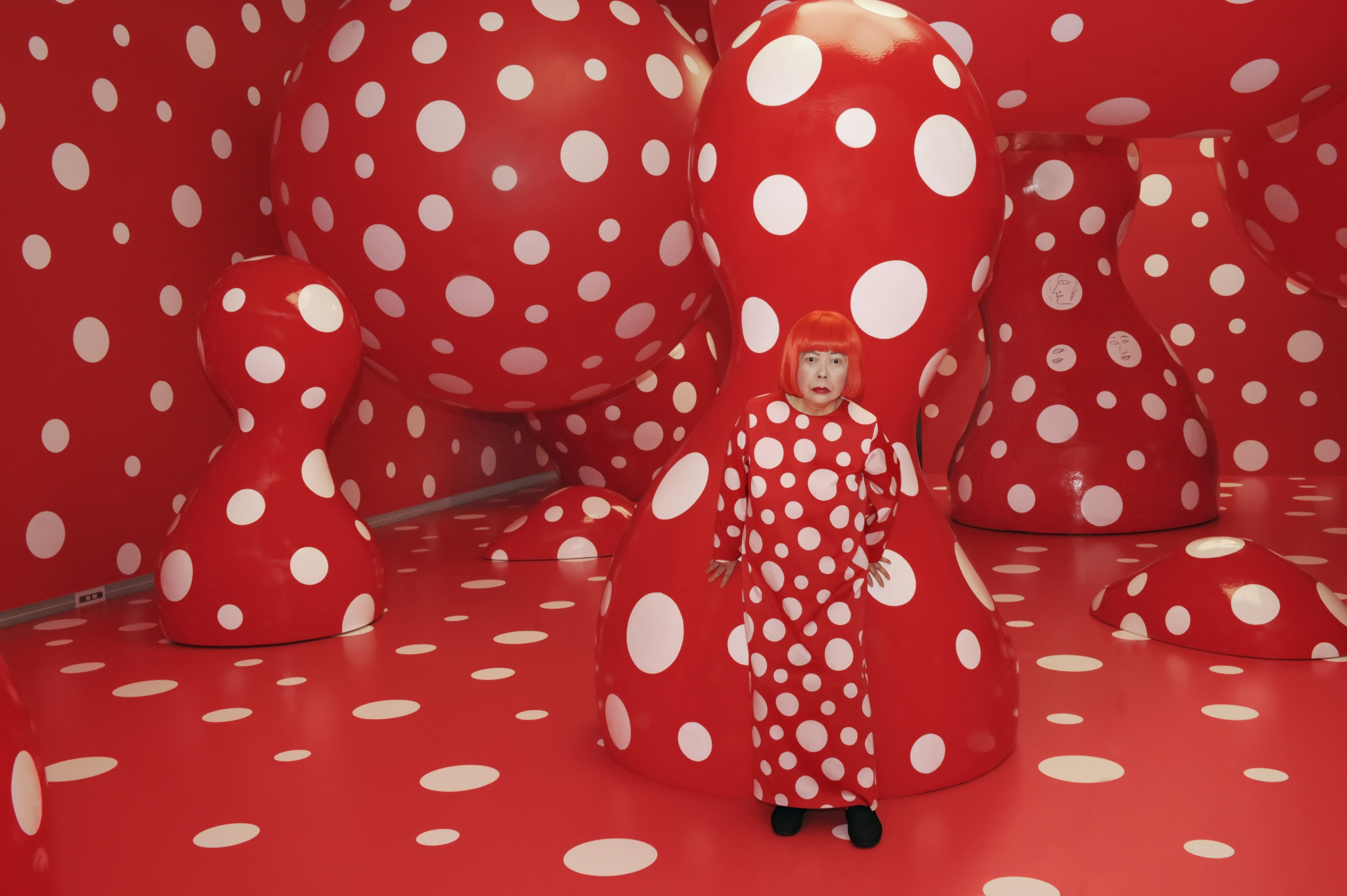 Okay, let's break down this image through the lenses you've requested. **Visual Description** The image depicts Yayoi Kusama, a Japanese contemporary artist, fully immersed in one of her iconic "Infinity Mirror Rooms,...