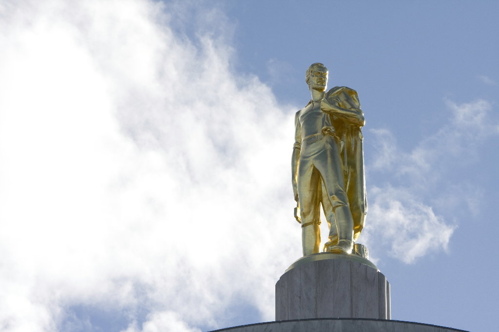 Here's an analysis of the image, broken down into the requested sections. Due to the image's nature, some sections will be more developed than others. **Visual Description** The image depicts a gilded statue of a man,...