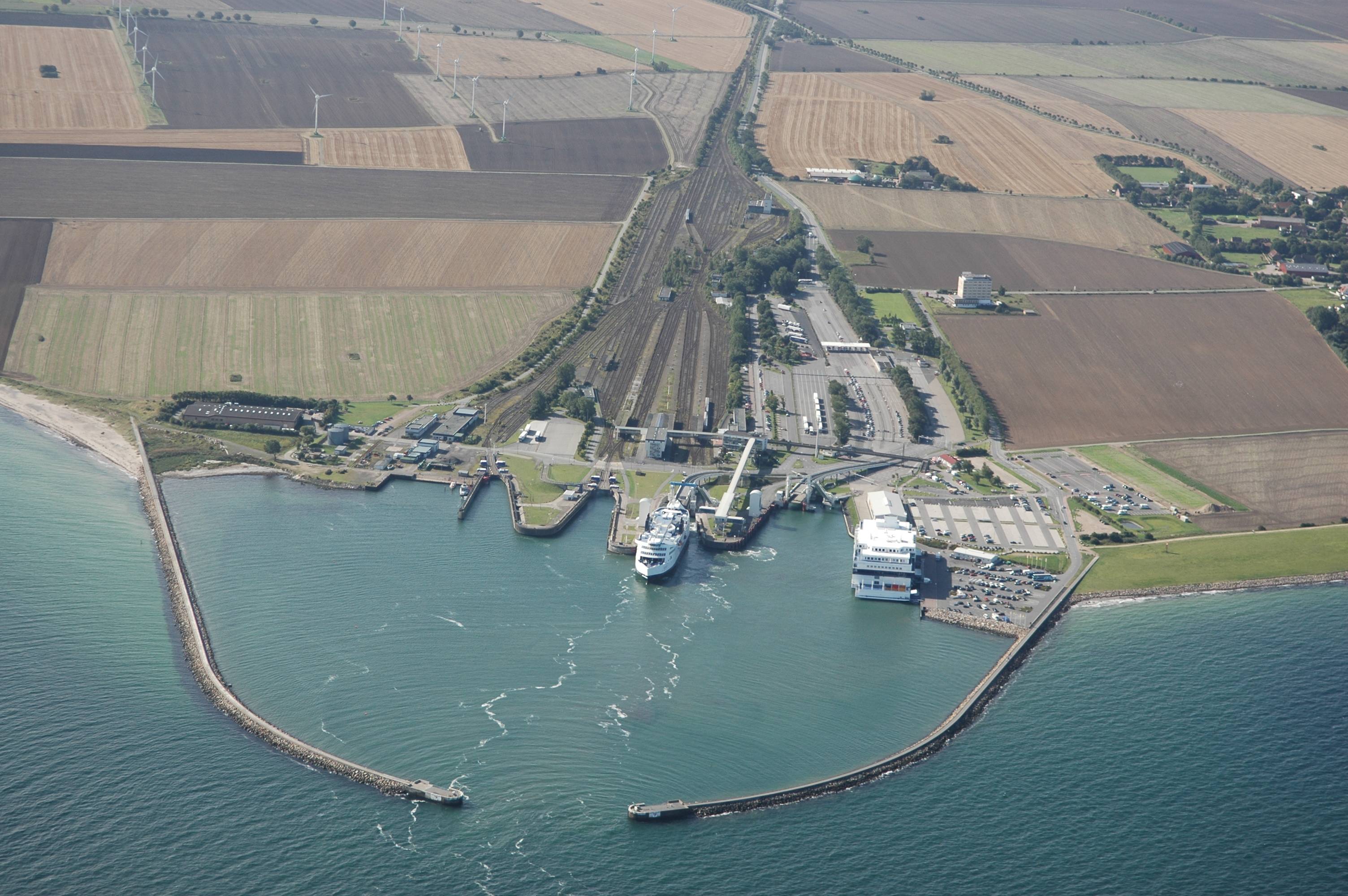 Okay, let's break down this aerial view of what appears to be a ferry terminal and surrounding landscape through the lenses you've requested. Not every lens will be strongly applicable, and I'll explain why if that's...