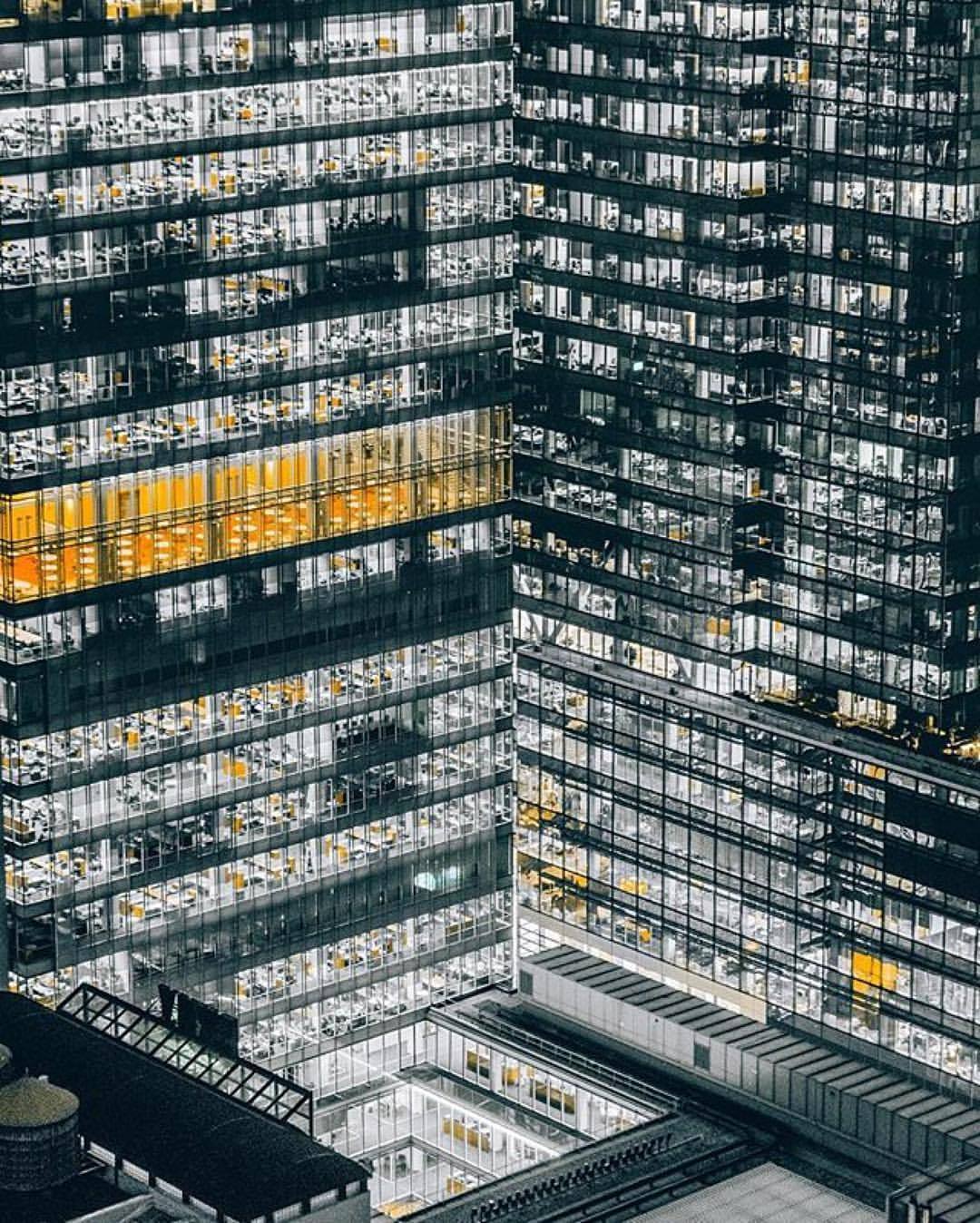 Okay, let's break down this image through a series of analytical lenses. **Visual Description** The photograph presents a high-angle, almost aerial view of a modern, multi-story office building. The dominant feature i...